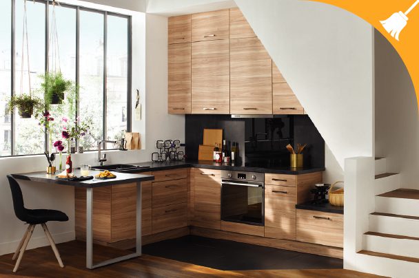 Modern kitchen with light wood cabinets, black countertops, built-in oven, and a small dining table by a large window; stairs are visible on the right.